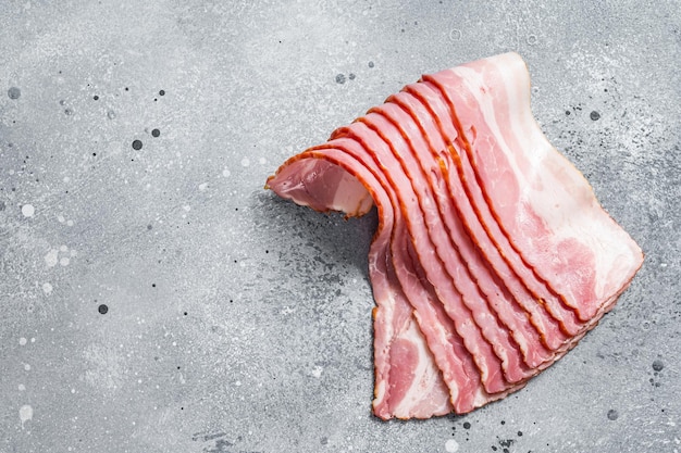 Raw bacon strips of pork meat Gray background Top view Copy space