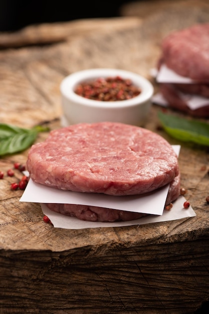 Raw beef meat burger steak cutlets and dry red pepper wooden background