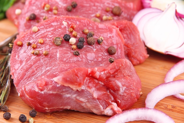 Raw beef meat with spices on wooden background