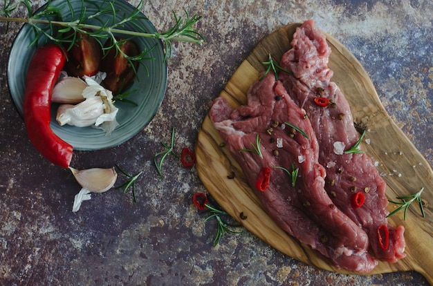 Raw beef meat with spices on a wooden board