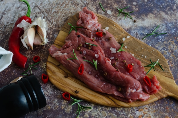 Raw beef meat with spices on a wooden board