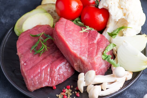 Raw beef steak on the bone with fresh vegetables in a grill pan on  concrete