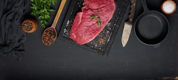 Raw beef tenderloin lies on a brown wooden board black table