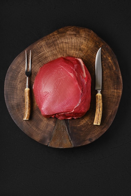 Raw beef top round meat on wooden slab