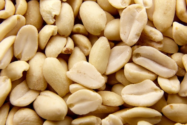 Raw blanched peanuts as food background closeup