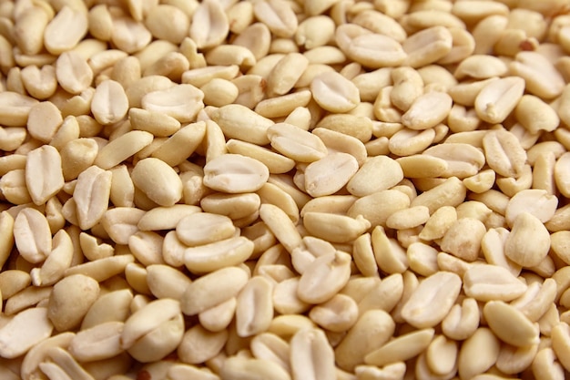 Raw blanched peanuts as food background closeup