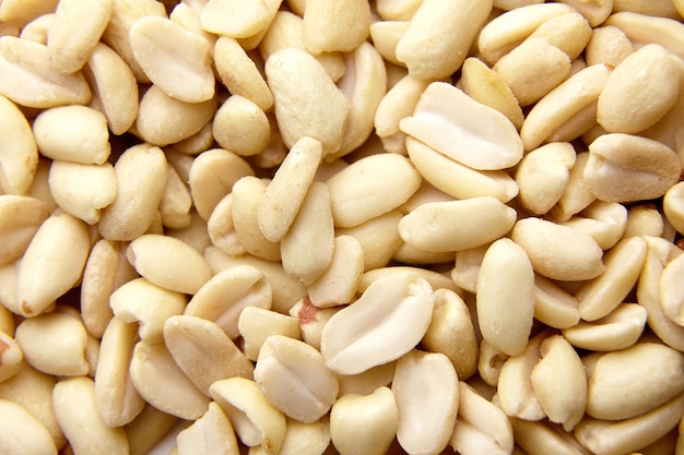 Raw blanched peanuts as food background closeup