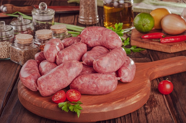 Raw brazilian sausages on the wooden board with ingredients