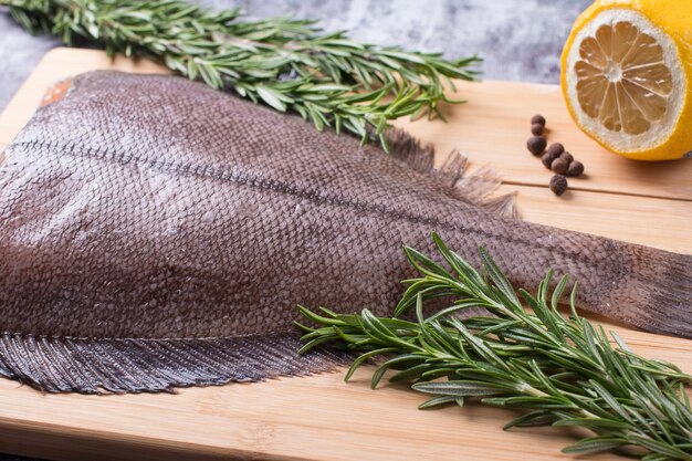 Raw butchered flounder on a cutting board with herbs and spices Seafood raw fish