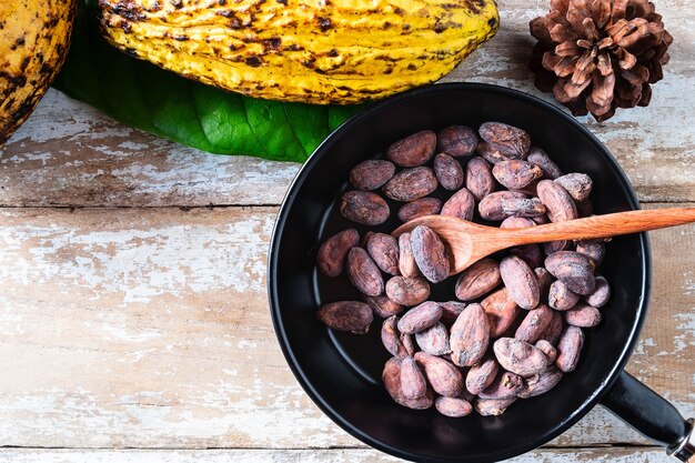 Raw cacao beans and cocoa pods on wooden boards.