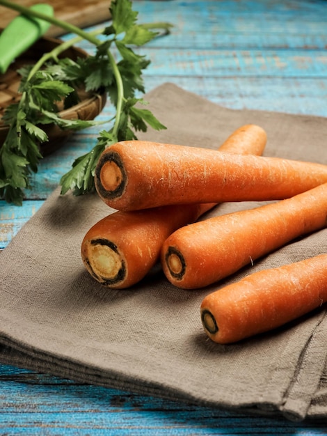 Raw Carrots on blue rustic table. Selective focus. Rough texture from carrots skin