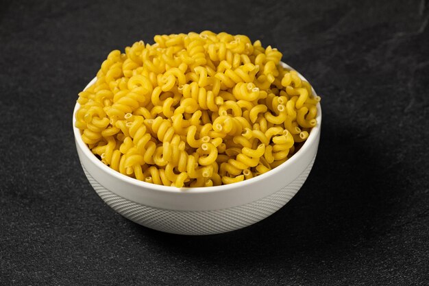 Raw Cavatappi Cellentani pasta in a plate isolated on dark background