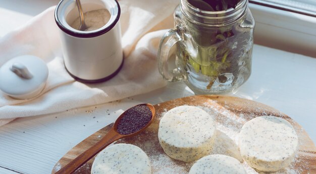 Raw cheese cakes with poppy seeds on a wooden surface