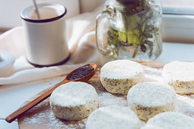 Raw cheese cakes with poppy seeds on a wooden surface