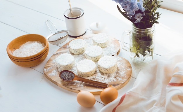 Raw cheese cakes with poppy seeds on a wooden surface