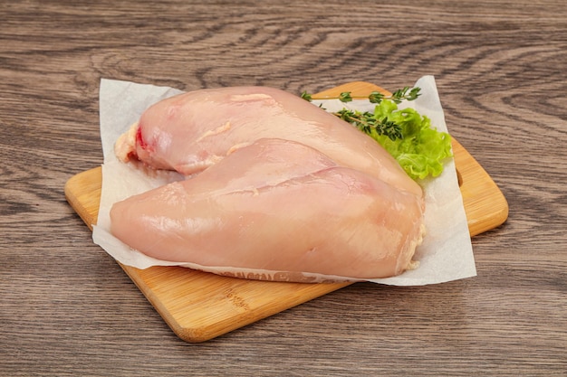 Raw chicken breast over board