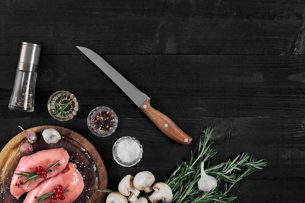 Raw chicken breast and condiments in a rustic wooden setting top view