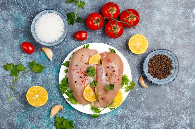 Raw chicken breast fillets on wooden cutting board with herbs and spices.top view