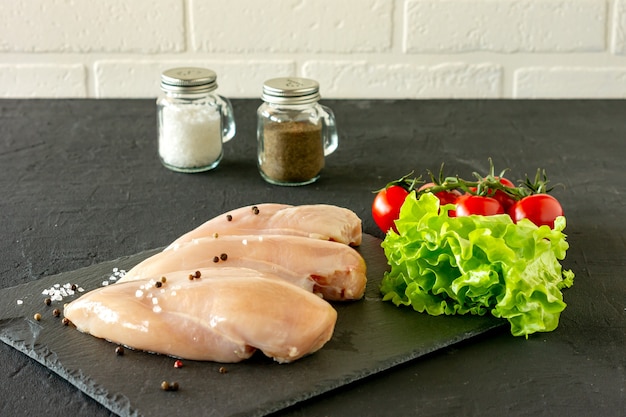 Photo raw chicken breasts with parsley and tomatoes ready for cooking. dietary food.