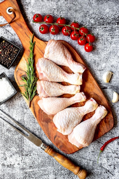 Raw chicken on a cutting board with tomatoes, garlic, and garlic.