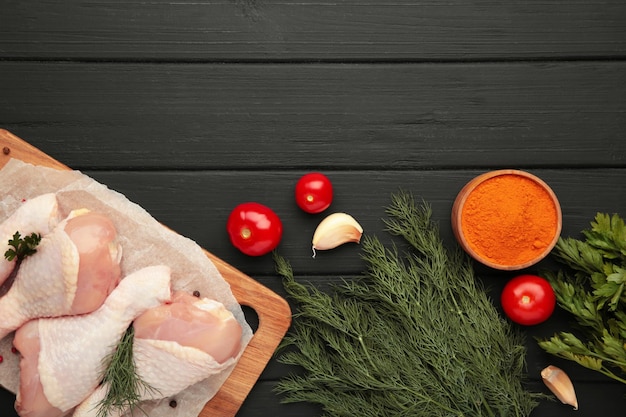 Photo raw chicken drumsticks with spices on cutting board on black wooden background top view free space for your text