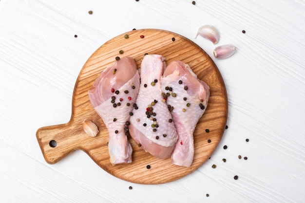 Raw chicken drumsticks on a wooden board Fresh chicken meat on a cutting board Top view from above