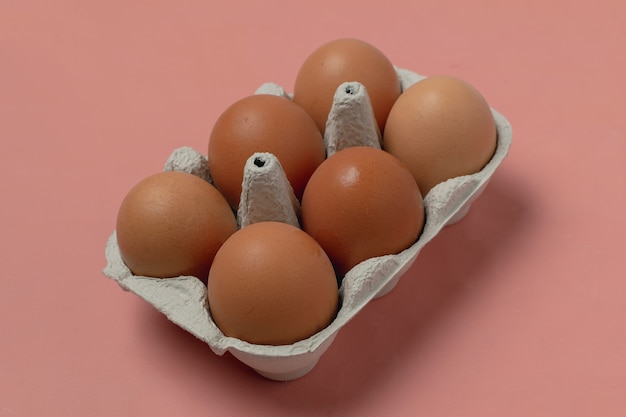 Raw chicken eggs in cardboard container on living coral