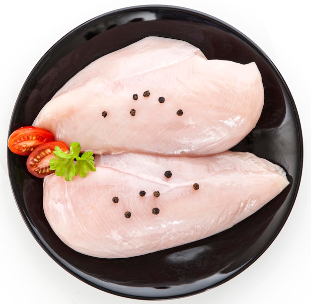 Raw chicken fillet on a black plate