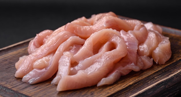 Raw chicken fillet cut into strips with spices and herbs