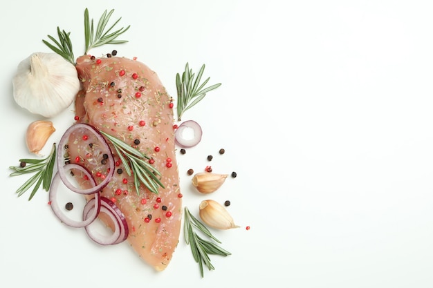 Raw chicken fillet with ingredients on white background