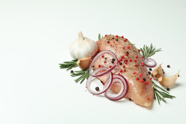 Raw chicken fillet with ingredients on white background