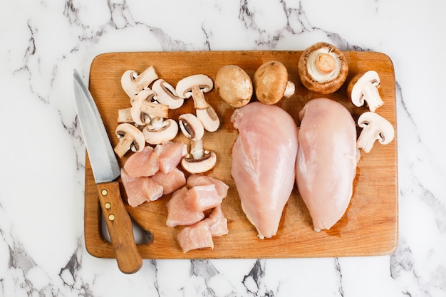 Photo raw chicken fillets on wooden cutting board, top view