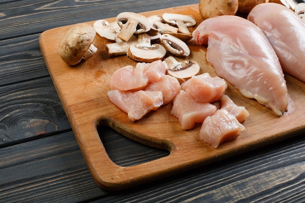 Photo raw chicken fillets on wooden cutting board, top view