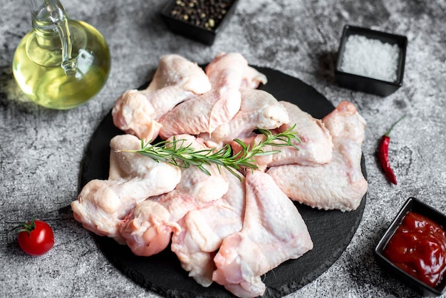 Raw chicken legs on a black stone plate with salt and salt.