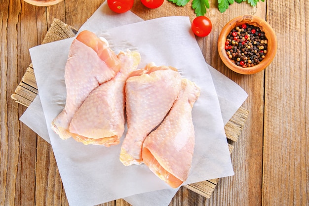 Raw chicken legs on a cutting board on an old wooden table.