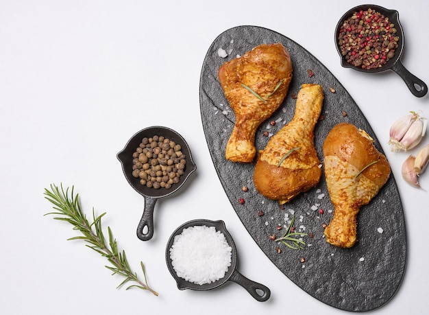 Raw chicken legs in spices on a black board top view Cooking with spices