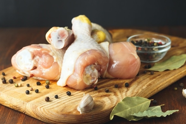 Raw chicken legs with spices on cutting board