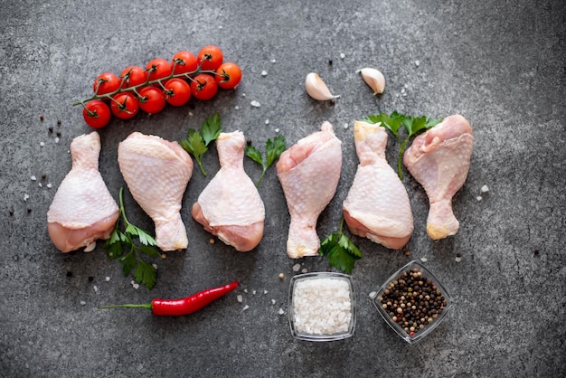 raw chicken legs with spices on a stone background