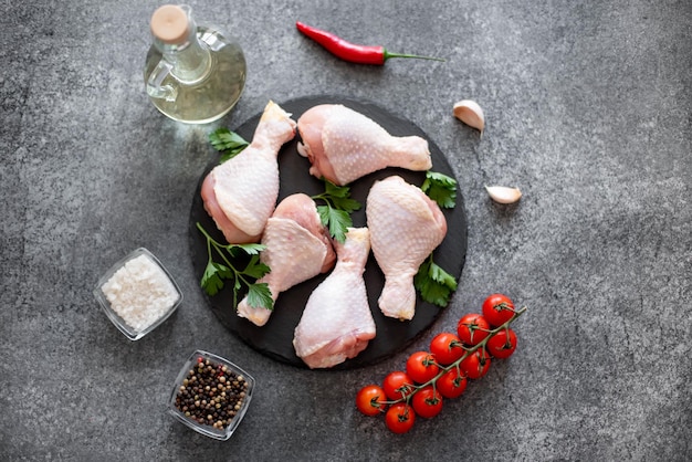 raw chicken legs with spices on a stone background