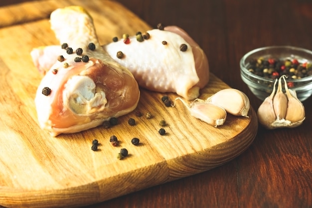 Raw chicken legs with spices on a wooden background