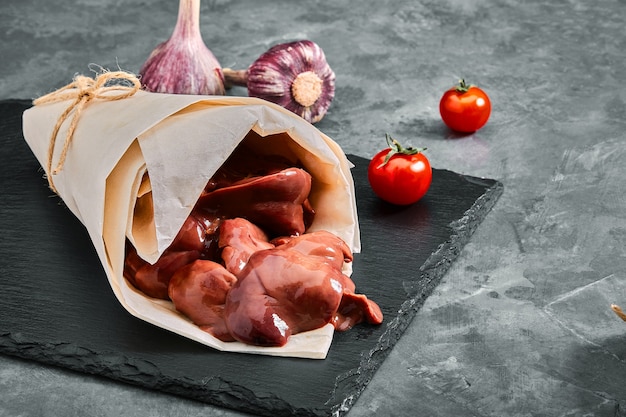 Raw chicken liver fillet on a gray cement background