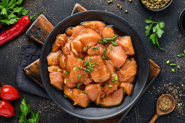 raw chicken meat marinated in teriyaki soy sauce, onions and pepper in a black plate