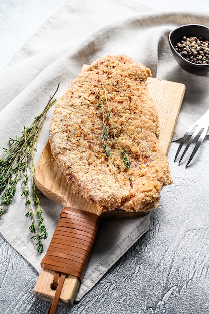 Raw chicken schnitzel in breadcrumbs. Gray background. Top view