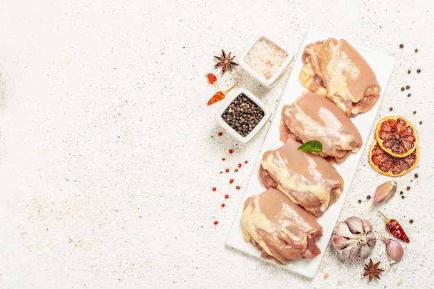 Raw chicken thigh without bones or skin. A useful ingredient for preparing healthy food, spices, garlic. Light putty background, top view