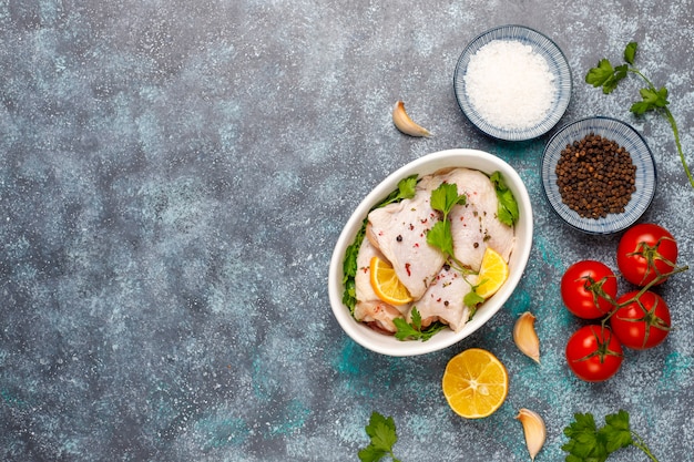 Raw chicken thighs with spices parsley on wooden cutting board,top view