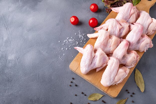 Raw chicken wing with spices on wooden board