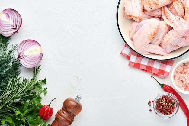 raw chicken wings in a white bowl with spices and ingredients for cooking 