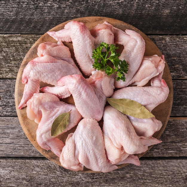 Raw chicken wings with ingredients for cooking on wooden board. Top view