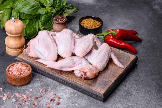 Raw chicken wings with ingredients for cooking on a wooden cutting board