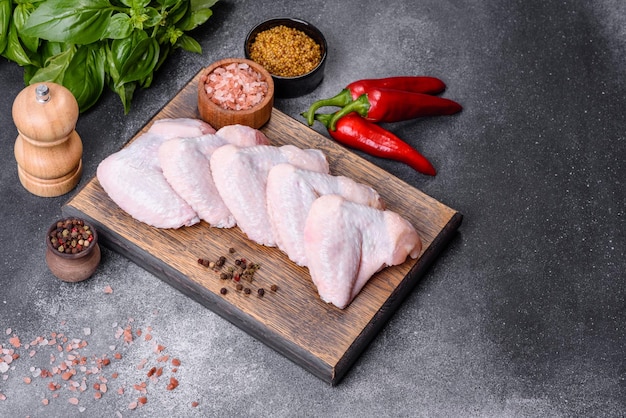 Raw chicken wings with ingredients for cooking on a wooden cutting board